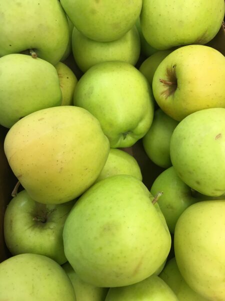 Fresh green apples piled together, showcasing their vibrant color and smooth texture, ideal for healthy snacking or baking.